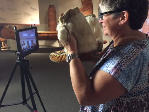 Woman stands in front of a camera and tripod 