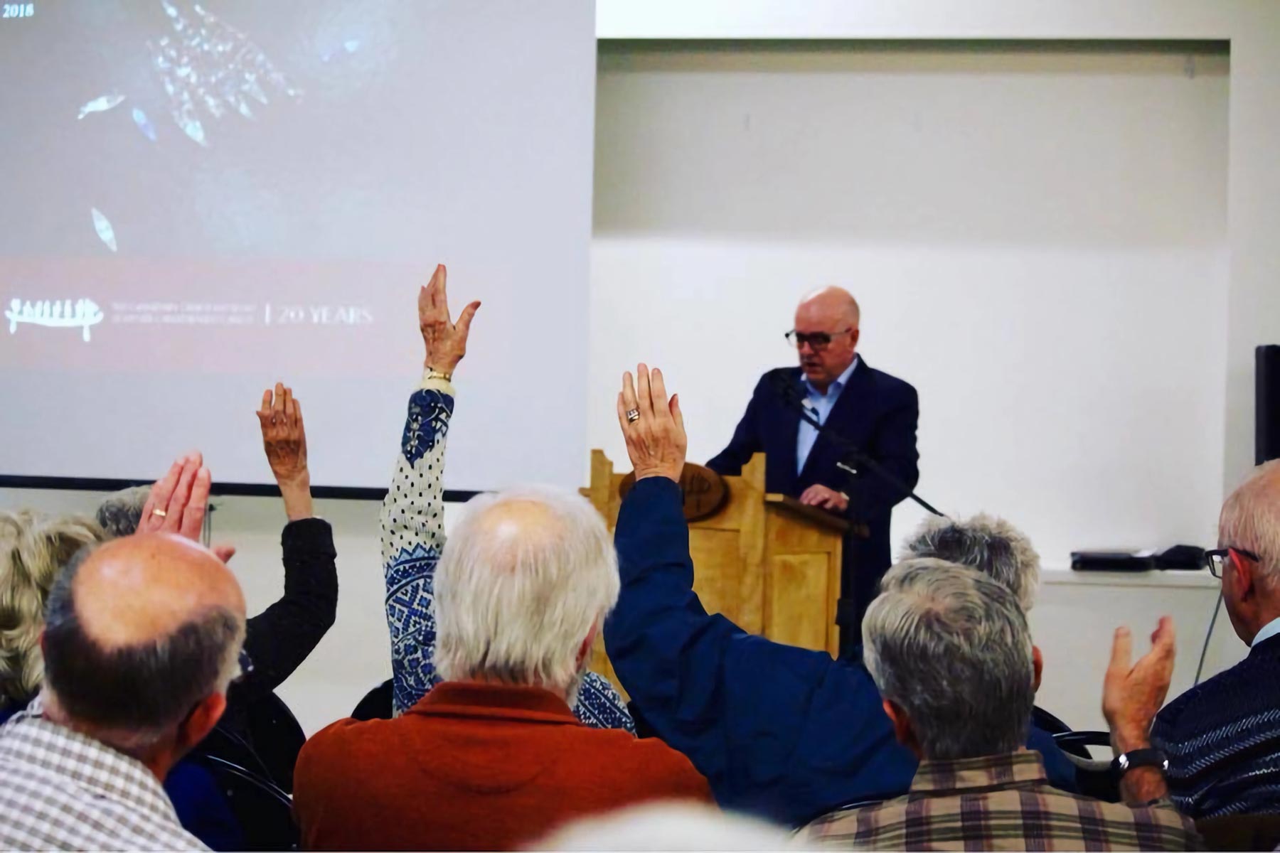 Members of The Canadian Canoe Museum raise their hands to vote during an Annual General Meeting.