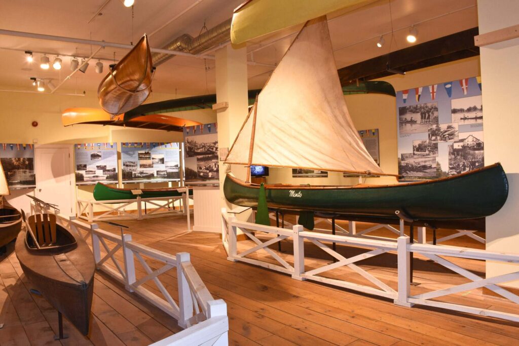 Exhibit showcasing several different canoes displayed on stands and hanging from ceiling.