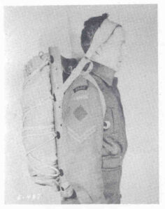 An old and faded black and white photo of a uniformed man wearing a Canadian tumpline backpack.