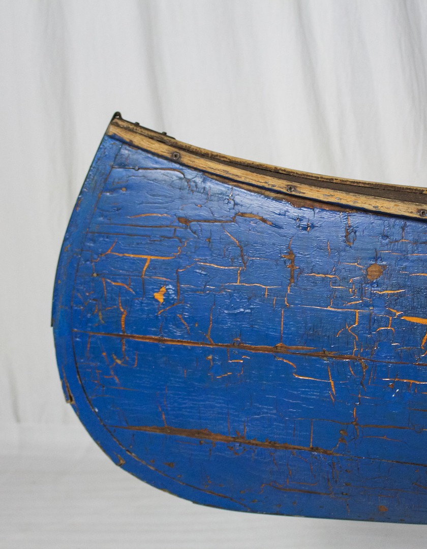 Cracked blue paint covers the stern of a wooden canoe in The Canadian Canoe Museum's collection.