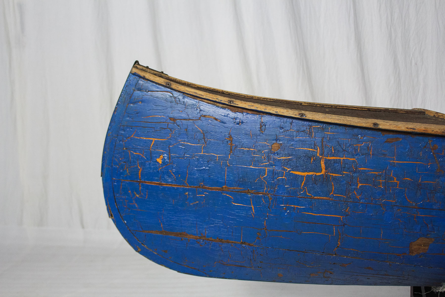 Cracked blue paint covers the stern of a wooden canoe in The Canadian Canoe Museum's collection.