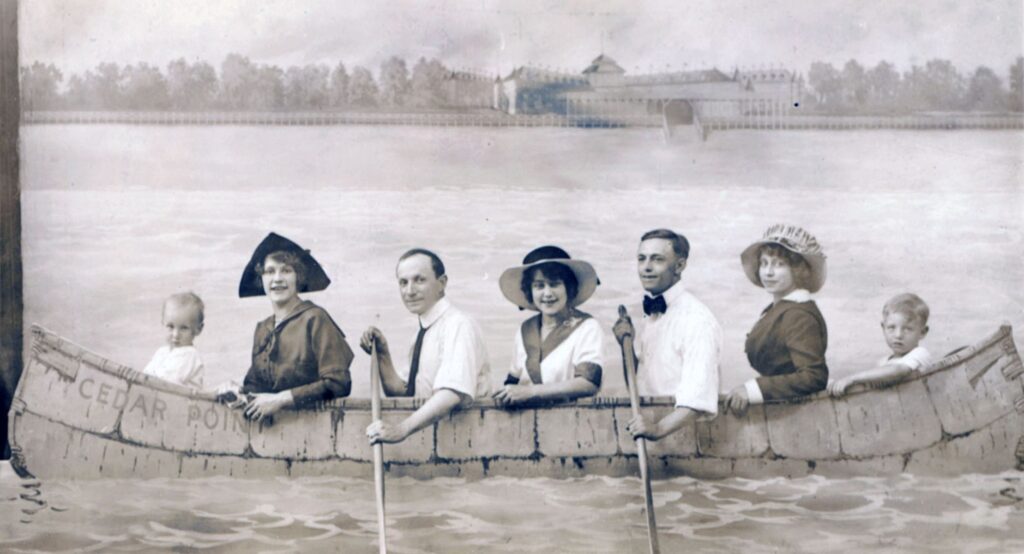 Black and white photograph of a family posing while paddling a large canoe