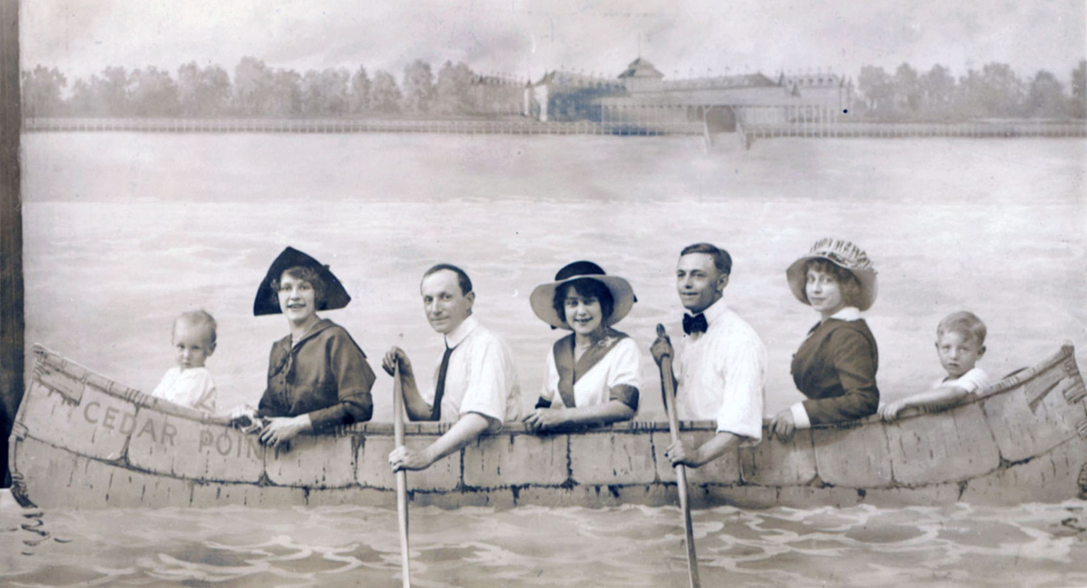 Black and white photograph of a family posing while paddling a large canoe