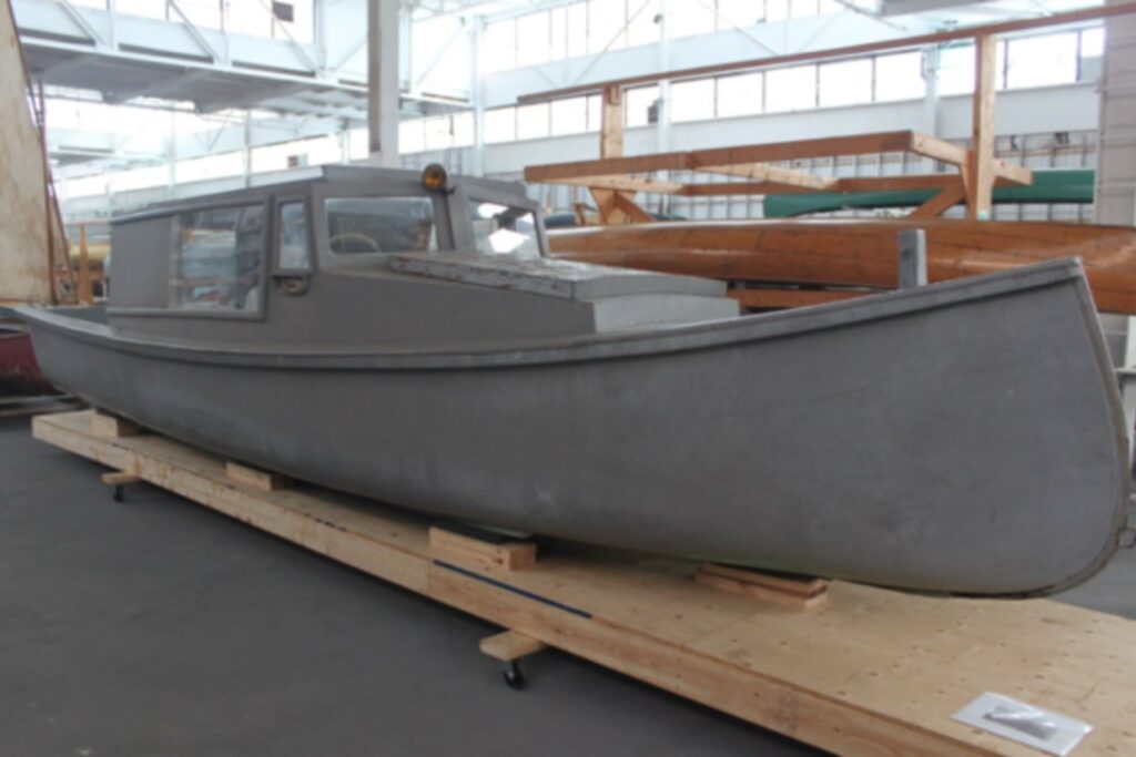 A large grey freighter canoe sits in a large storage garage.