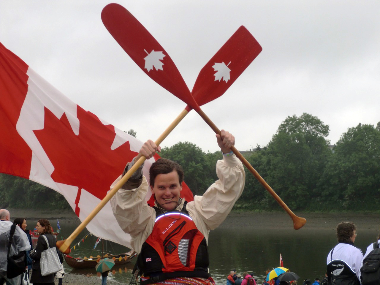 Geordie Dalglish smiles and holds two Canadian paddles up in the air.