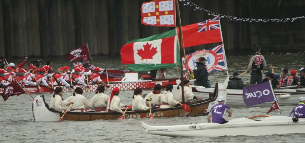 Several international teams sport their country's flag while paddling through the River Thames.