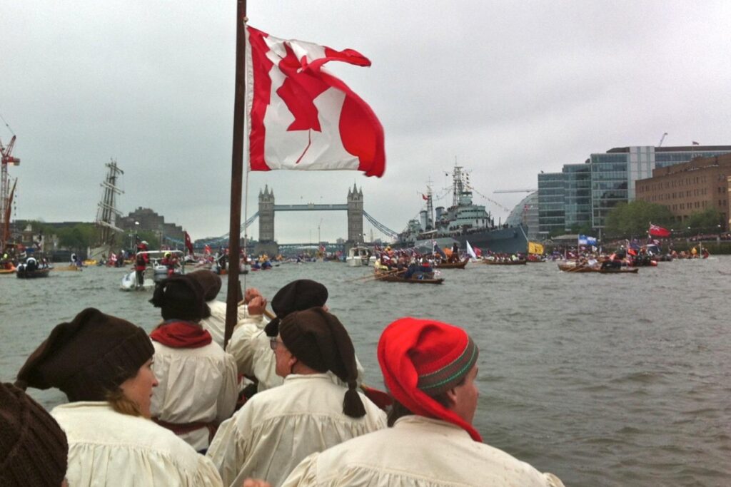 The team paddles the River Thames sporting the Canadian flag with Tower Bridge ahead.