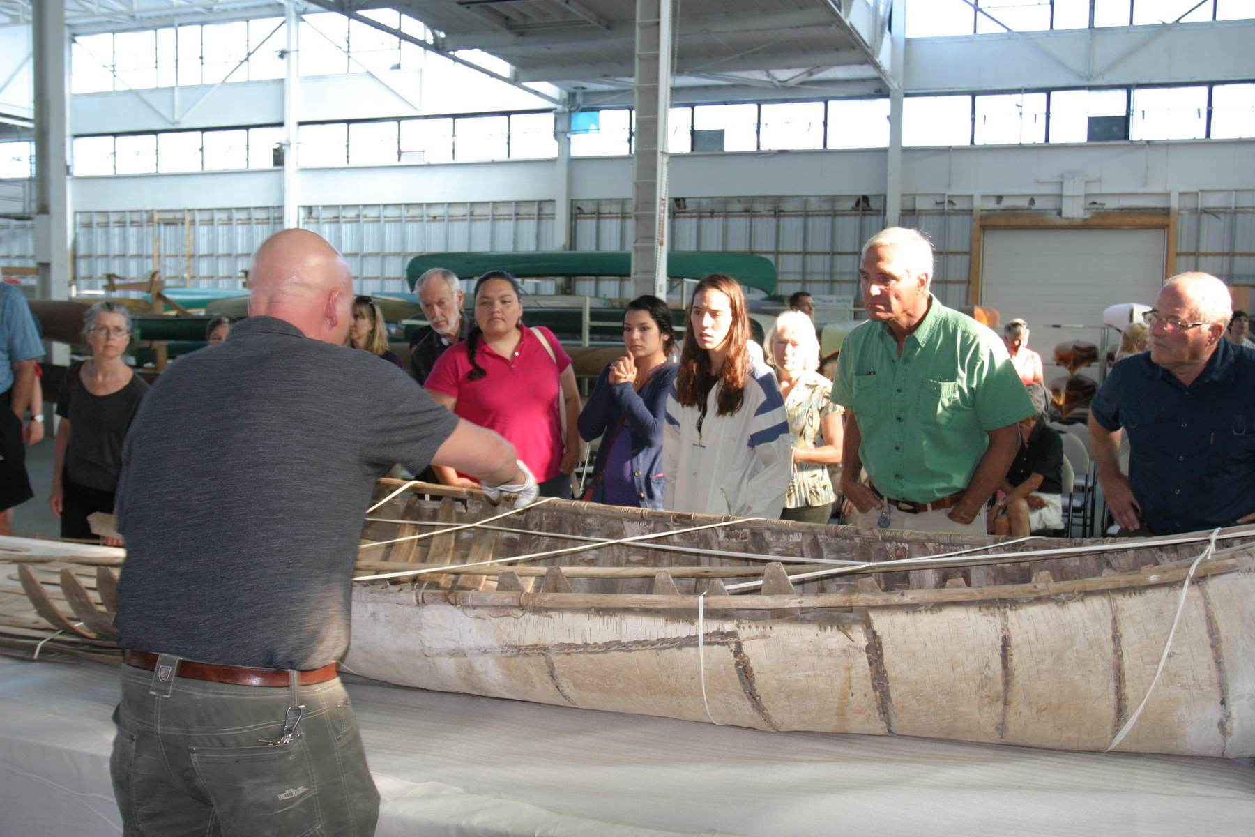 People gather closely around a canoe on display at an event