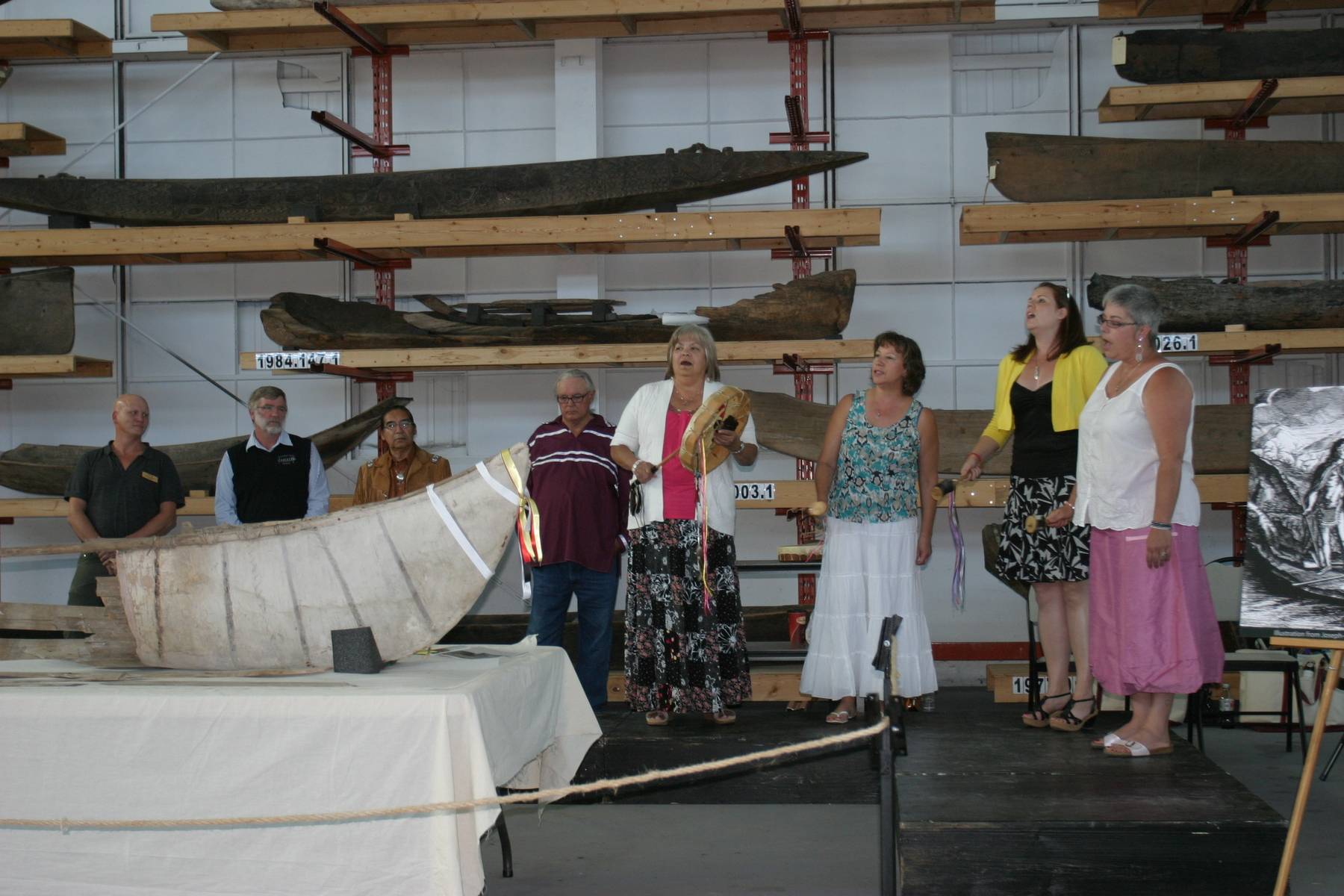 People have gathered around a canoe on display at an event