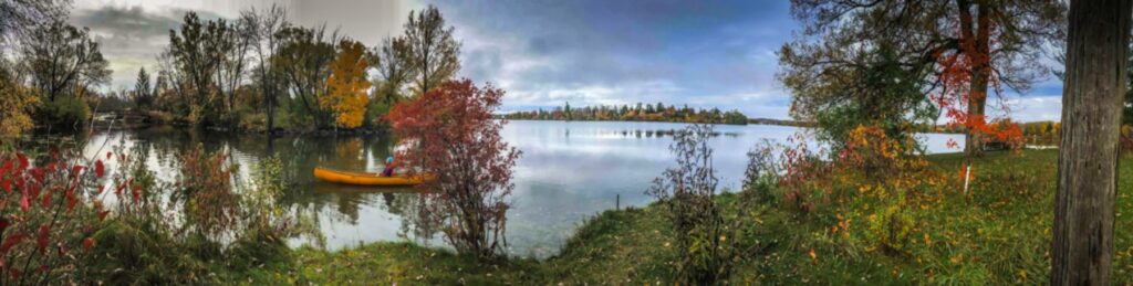 Canoeist paddles through Johnson Park in early autumn in a yellow canoe