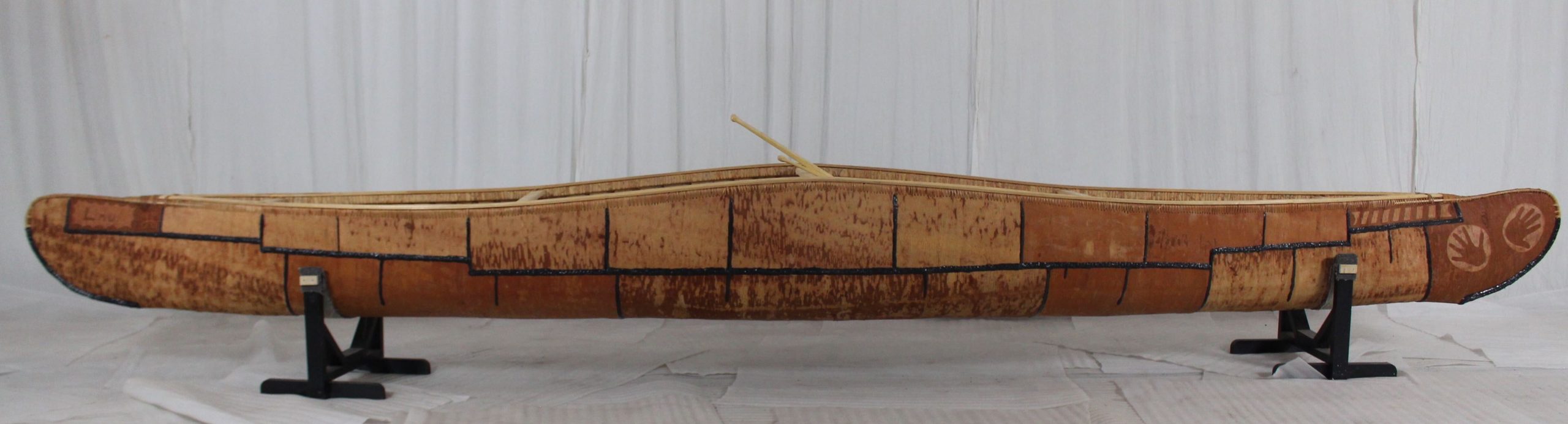 A single canoe displayed on a stand with a white background.