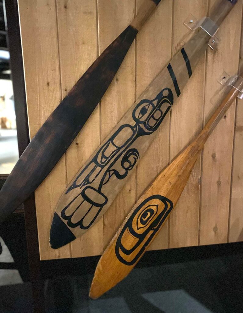 Three wooden canoe paddles on display