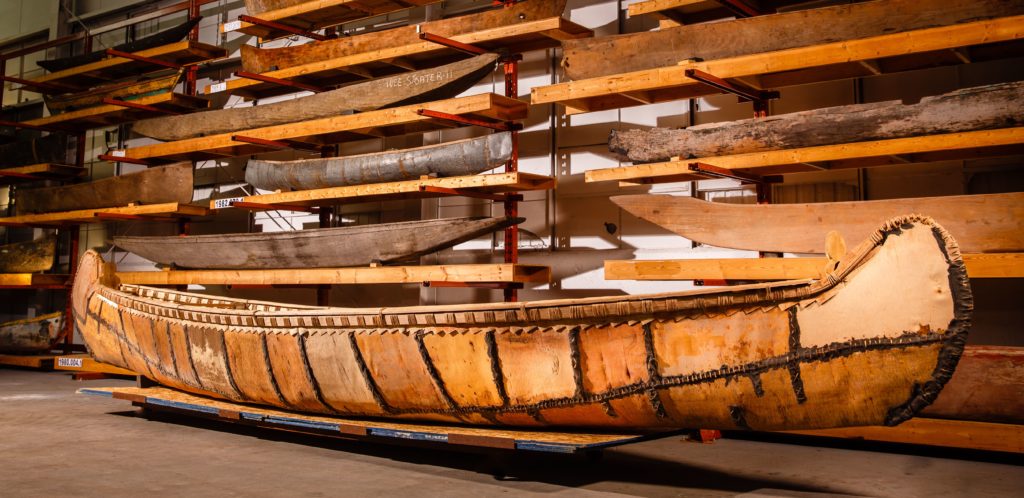 A single birch canoe on a moving stand.