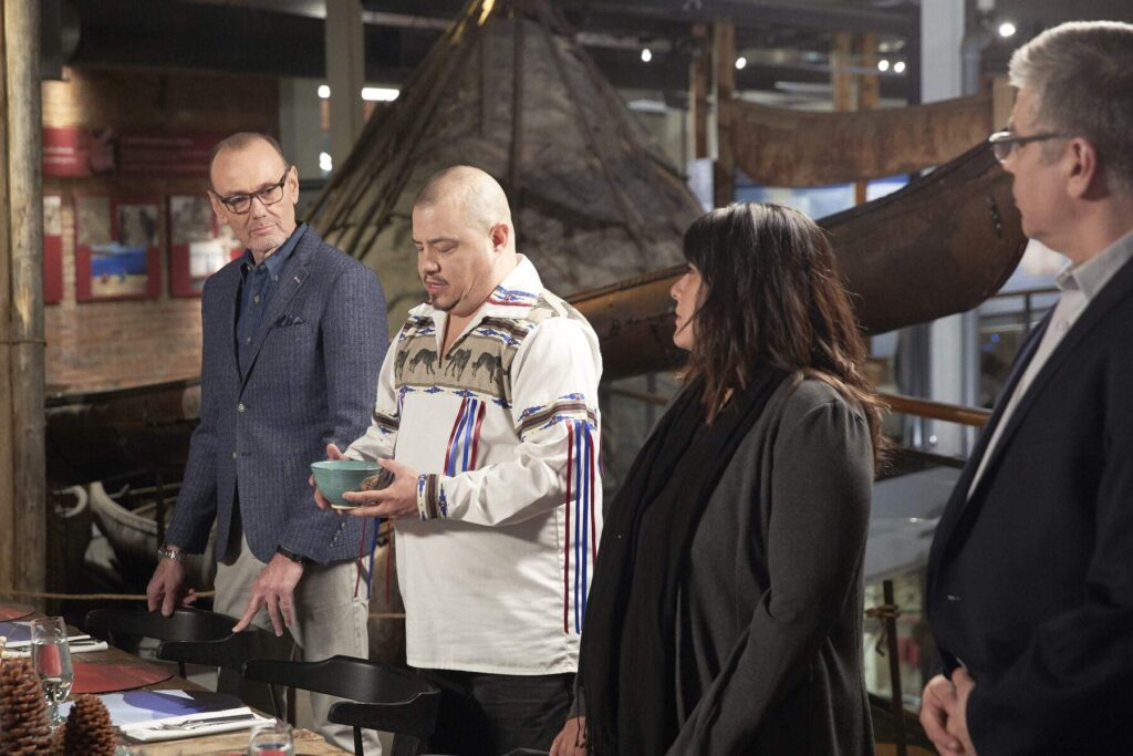 Four people standing at a table while one holds a bowl of food