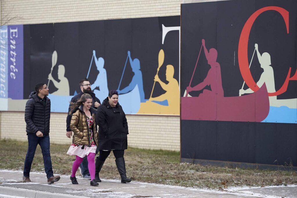 Four people walking on a sideway alongside the Canoe Museum