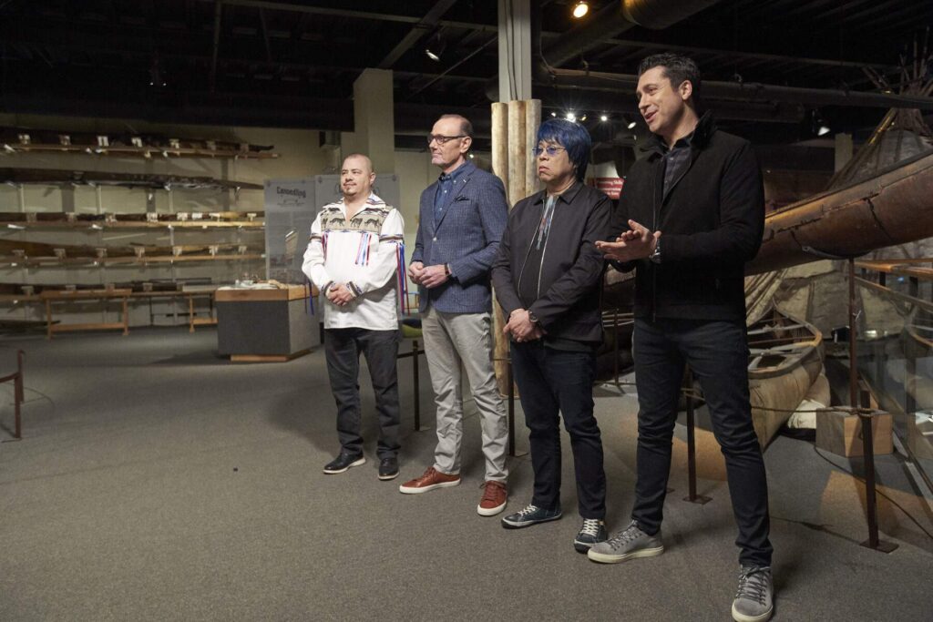 Four people stand in front of a canoe display