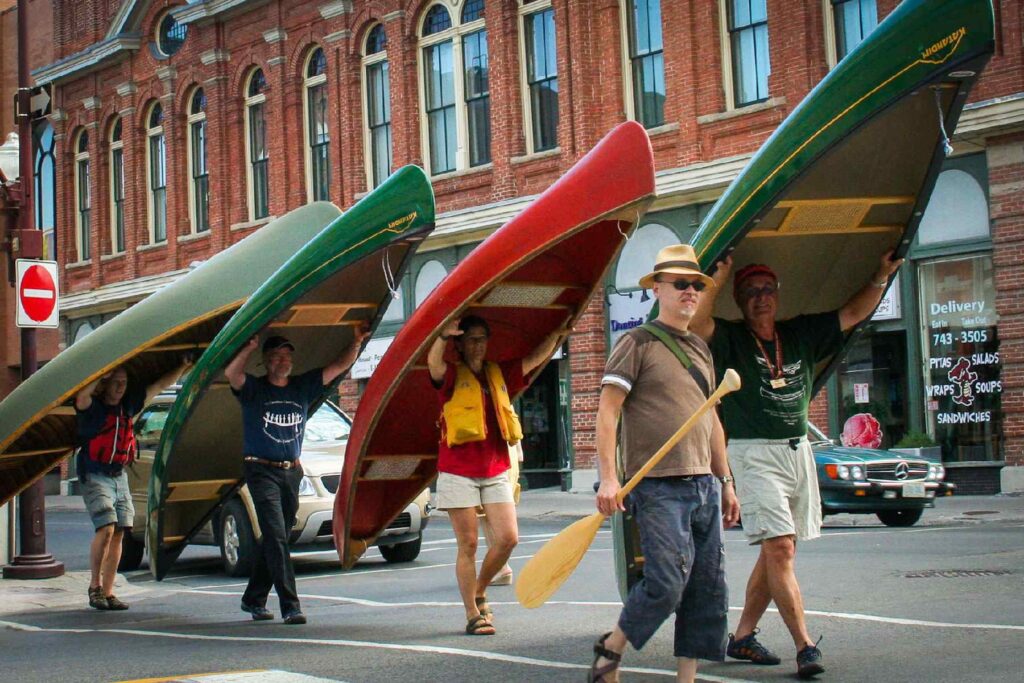 Group of people solo portaging canoes downtown Peterborough.