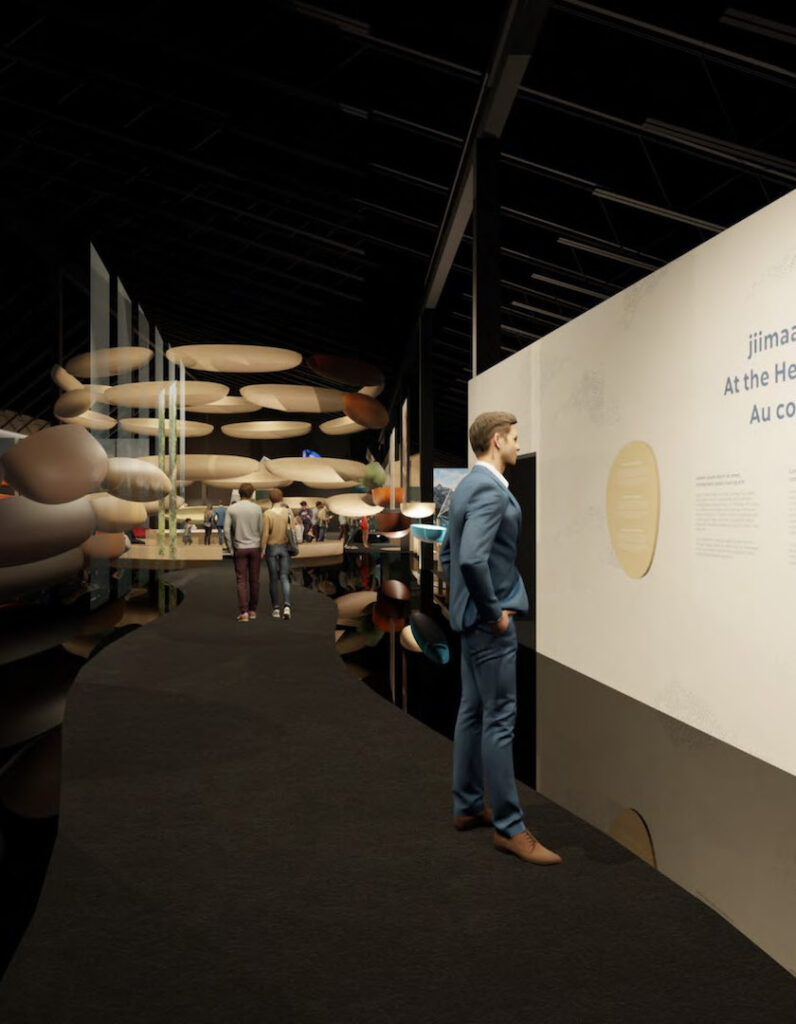 A concept render of the entrance to The Canadian Canoe Museum's Exhibition Hall. A man in a suit stands reading a text panel, while in the background visitors make their way through the exhibits.
