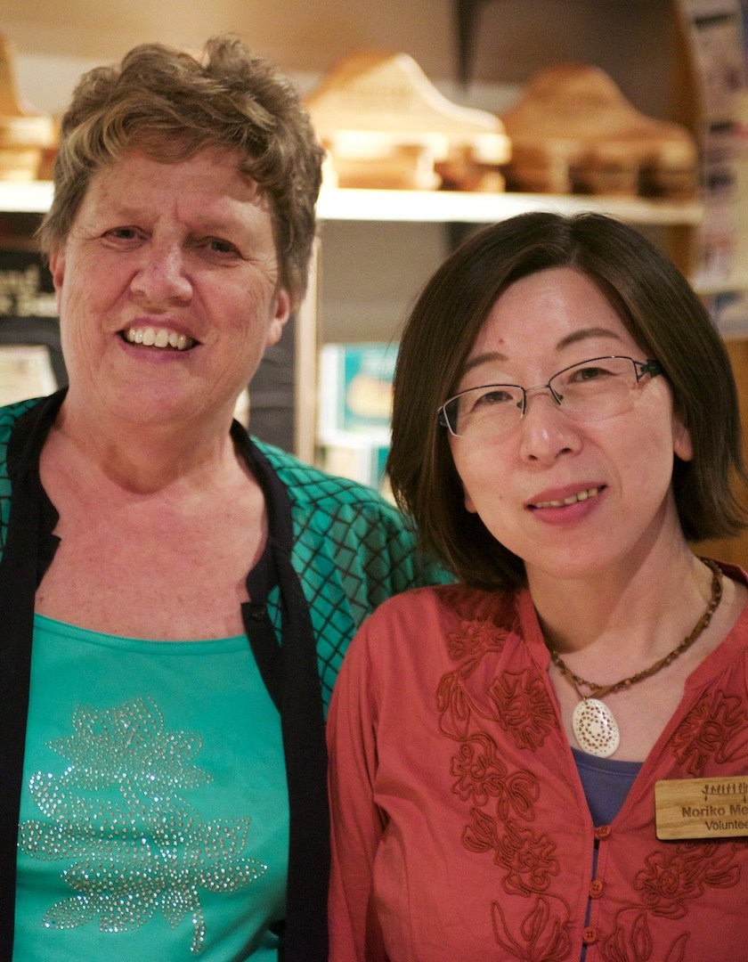 Two volunteers stand smiling in The Canadian Canoe Museum's gift store.
