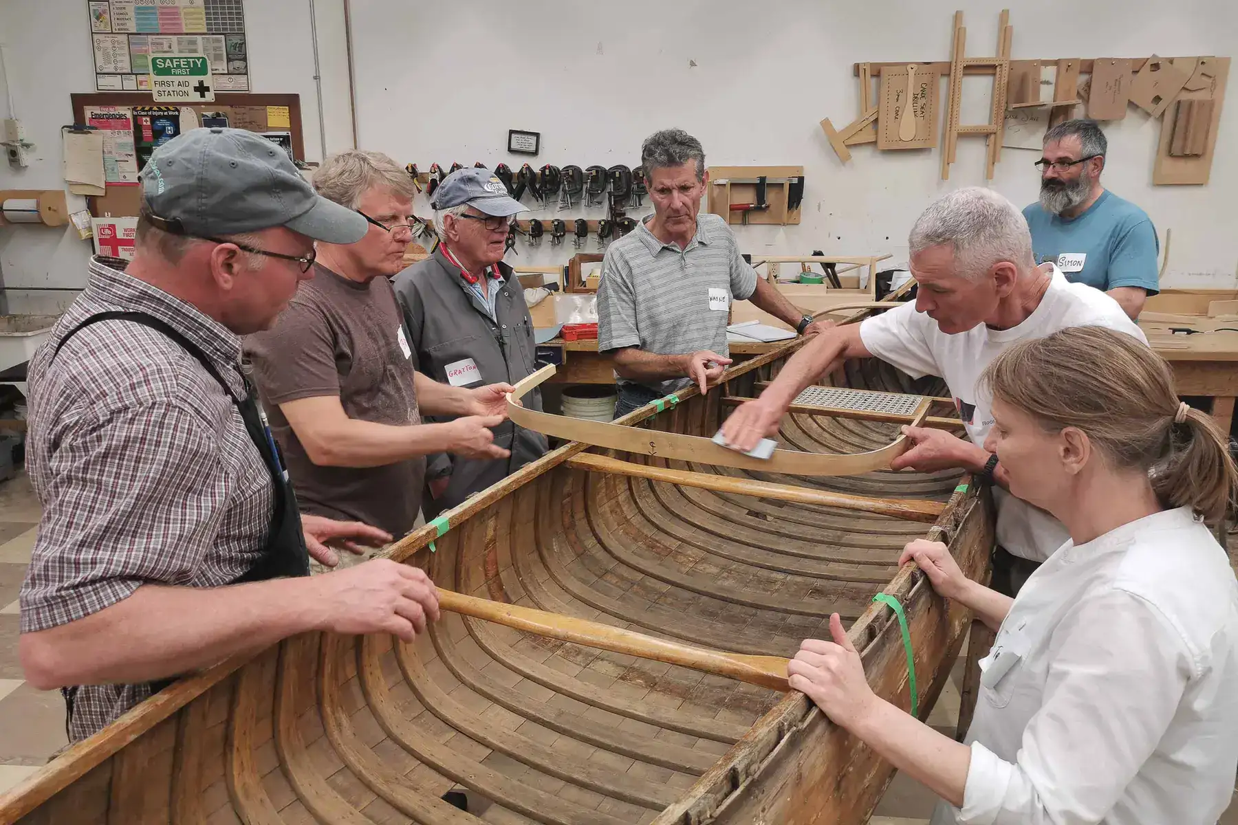Group of course attendees and instructor surrounding a canoe restoration project.