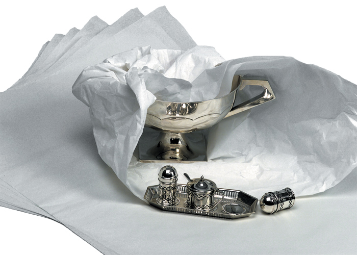 A polished silver bowl and silver tray partially wrapped with tissue.