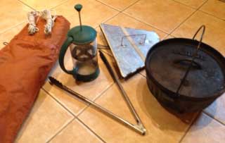 A collection of gear including a dutch oven, tongs, twine, and a coffee press