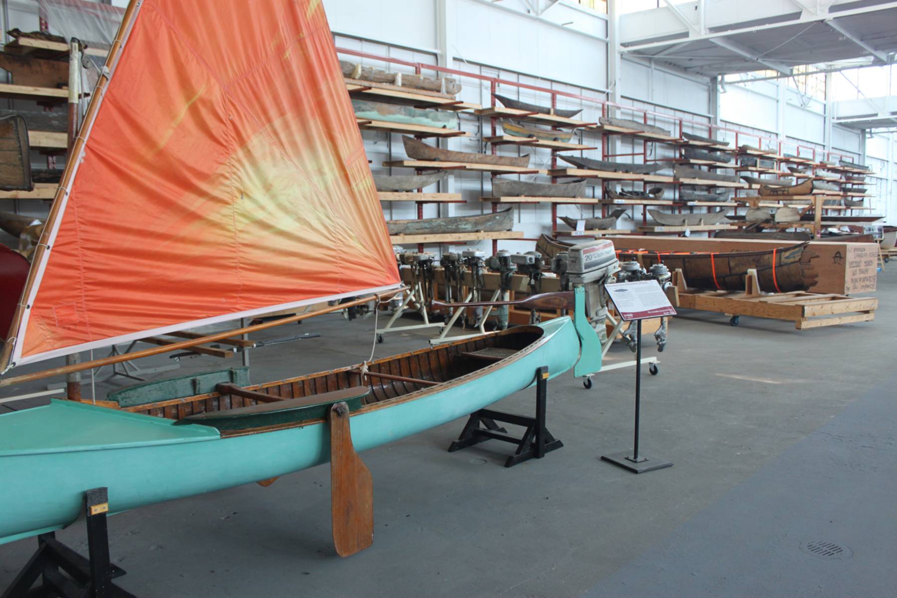 A bright blue canoe with an orange sail sits on a rack in the museum's storage facilities.