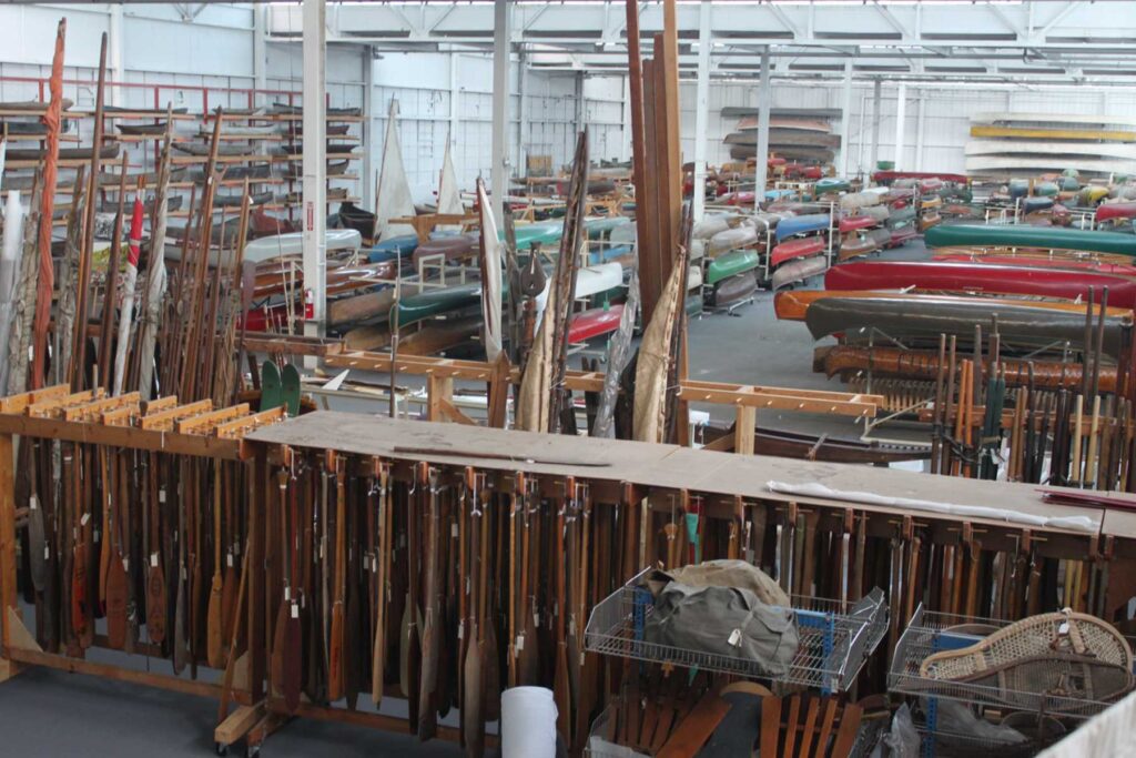 Large storage garage with rows of canoes and paddles