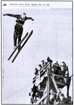 Black and white photograph of Ian Blaiklock skiing mid-jump with spectators in the background