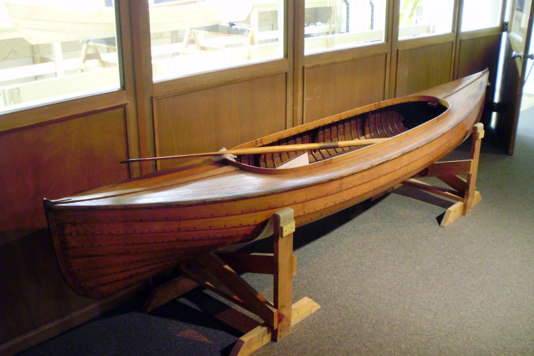 A wooden lapstrake canoe sits on display in the Preserving Skills gallery