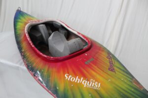 Multicolour tie-dyed kayak with worn stickers.