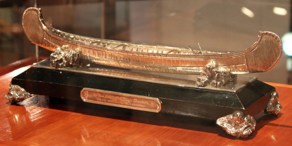 A small canoe made of silver sits on display